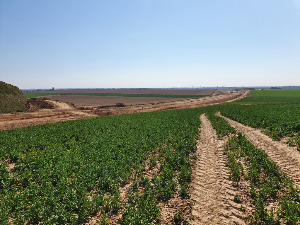 Pohled z Libin směr Hradec Králové. Zemní práce i propustky jsou hotové. V zářezu na úrovni Rožnova se již zelená zatravnění. V pozadí se rýsuje budoucí křižovatka Jaroměř jih.