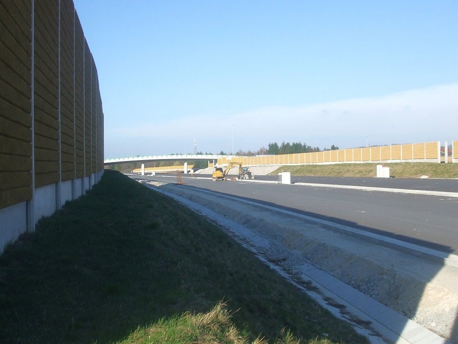 Pohled směrem k MÚK Pohůrka, v pozadí přemostění dálnice ulicí Ke Studánce